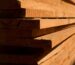Close-up view of stacked wooden planks showcasing texture and sunlight shadows.